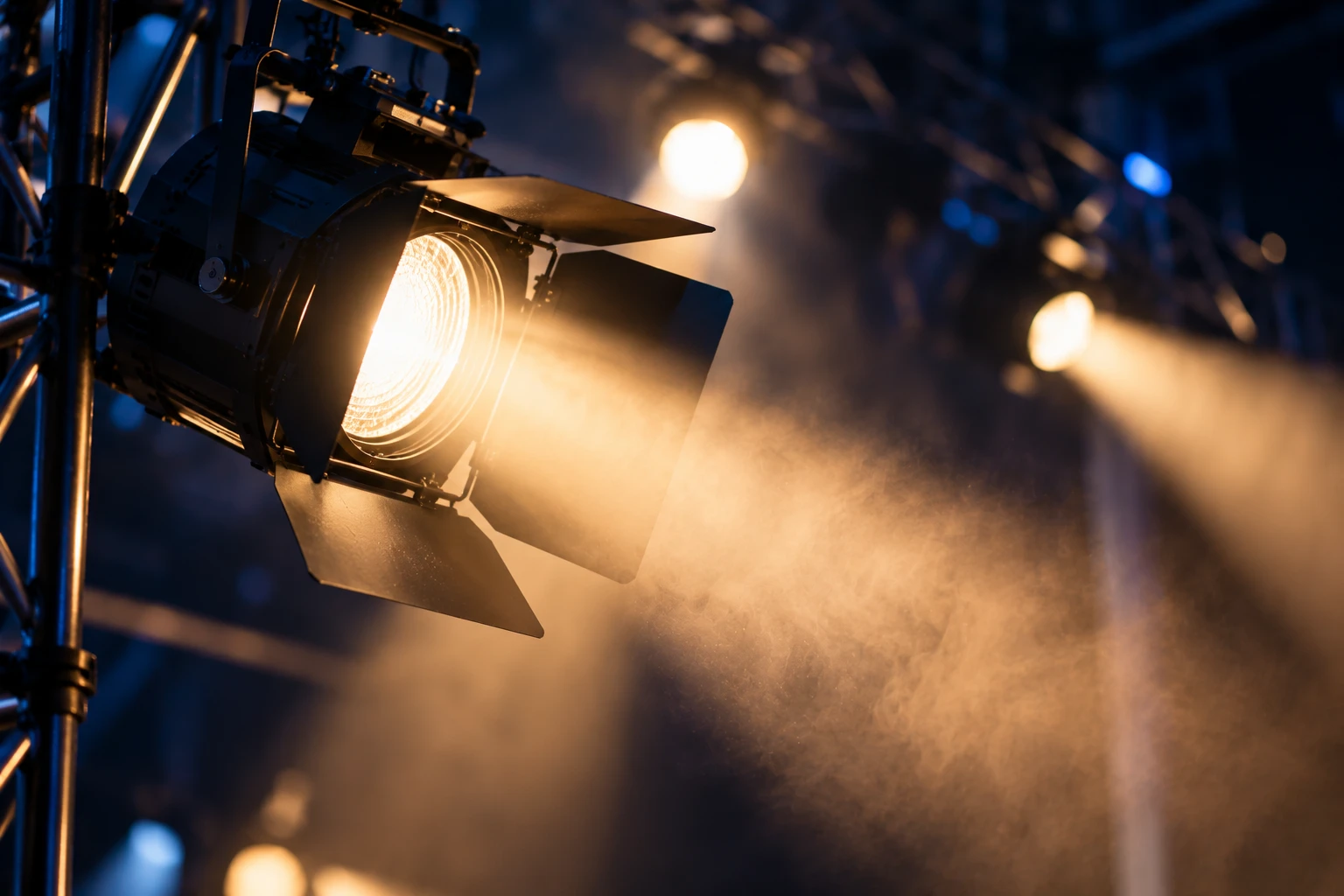 A fresnel stage lamp throwing a warm beam through haze.