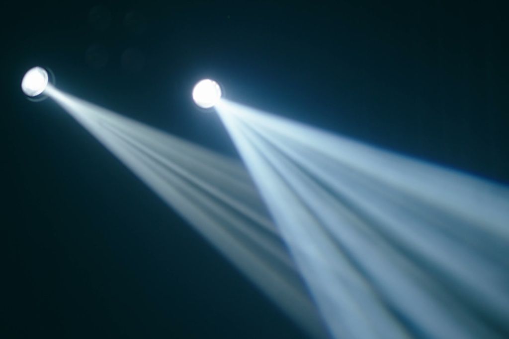 Two spotlight beams crossing in darkness.