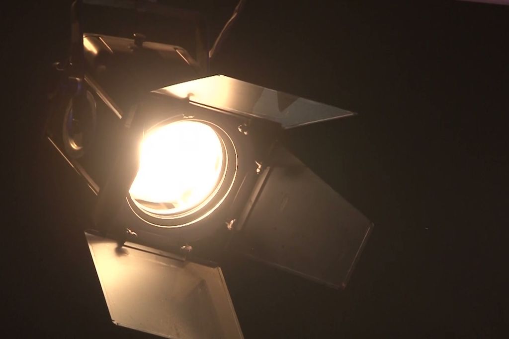 A single fresnel lamp against darkness.
